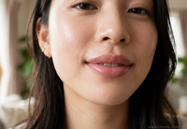 上品でほのかに艶のあるピンクベージュのリップを塗った、20代前半の日本人女性の唇のアップ。